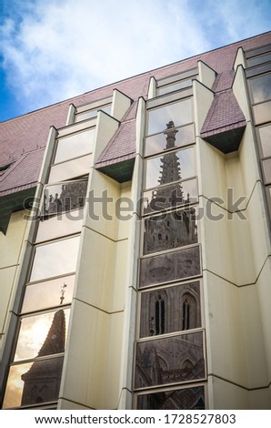 The spire of the famous Matthias Church in Budapest, Hungary in the window reflection on another historical building in the city center. Roman Catholic church built in Gothic style. Vertical photo.