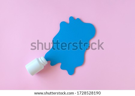 White pill packaging with blue paper splash on pink background. Medicine concept. 