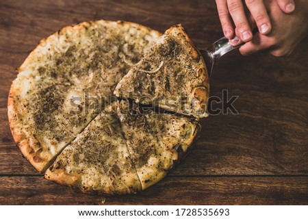 Hand serving a Delicious iItalian pizza served on rustic wooden table- top view of Italian pizza with ingredients- 