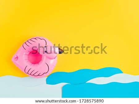Inflatable pink flamingo, paper sea waves. Summer vacations and beach, seaside holidays, parties concept