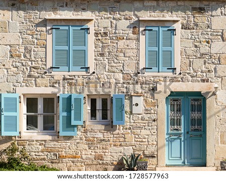 Exteriorof a stone village house with wooden windows and door. Turquoise blue blinds of an traditional house. Royalty-Free Stock Photo #1728577963