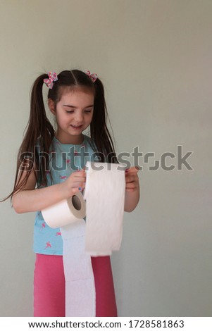 Portrait of a beautiful young girl with long blond hair and rolls of toilet paper. Photo joke.