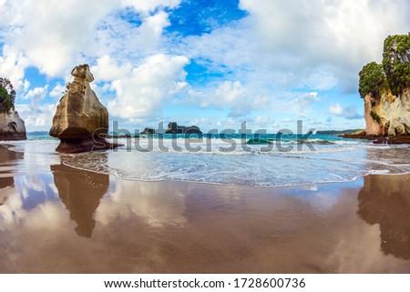  Bizarre clouds and coastal cliffs reflected in the tidal waters of the Pacific Ocean. Coromandel Peninsula. Cathedral Cave on the North Island. The concept of exotic, ecological and photo tourism