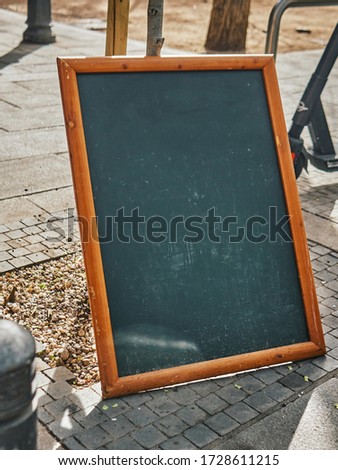 Chalk board with a wooden frame on the street near a small cafe. Summer