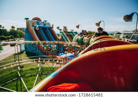 Cheerful young people enjoying in funfair and riding in roller coaster train
