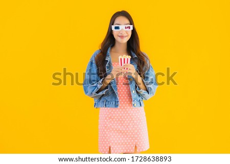 Portrait beautiful young asian woman enjoy happy with phone popcorn and watch movie on yellow isolated background