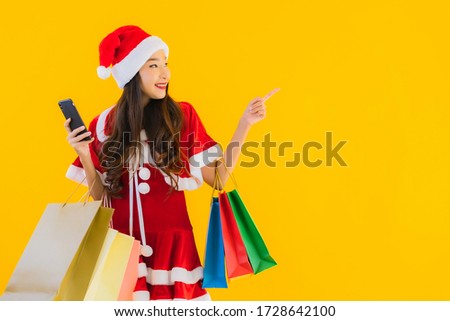 Portrait beautiful young asian woman wear christmas clothes hat with a lot of shopping bag on yellow isolated background