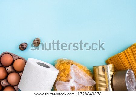 Food supply quarantine food crisis crisis isolated on blue background. Chicken eggs, quail eggs, pasta, canned food, toilet paper. Food Delivery, Donation, Coronavirus Quarantine. Copyspace. Flat lay