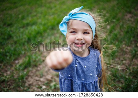 little girl child runs on green grass in the field, sunny spring weather, smile and joy of the child, blue sky with clouds