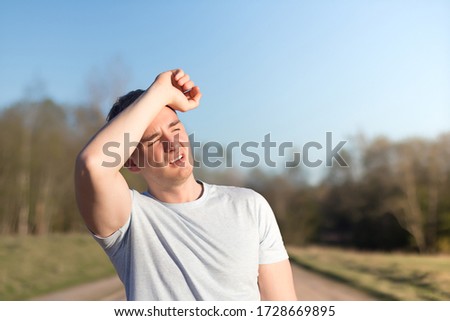 young man athlete received sun and heat stroke and headache. guy holds his head with his hands and protects himself from the sun in outdoors. copy space, place for text Royalty-Free Stock Photo #1728669895