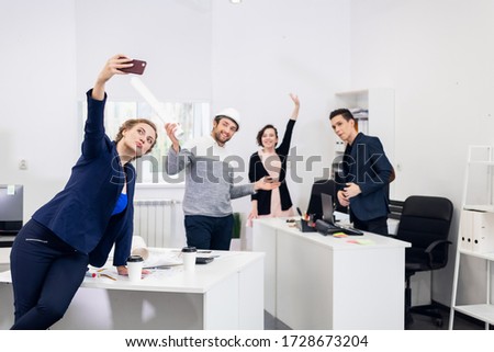 Employees having fun in the office, posing and taking selfies wi