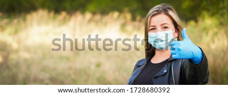Young blonde hair woman with her face mask and blue rubber gloves is on the walking in the park. She is looking forward to the end of corona virus - COVID 19 and quarantine.