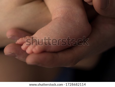 close-up. foot of a newborn on the arm of an adult. photo in a low key. image with selective focus