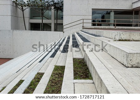 Close up to a Geometric pattern of a modern white street stairways with green grass, trees and nature architecture. 