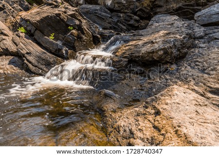 Nature Scene featuring beautiful waterfalls showing water streaming through rock crevices on a sunny day