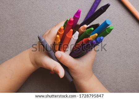Closeup of child's hands with colorful wax crayons pencils. learning concept. Flat lay