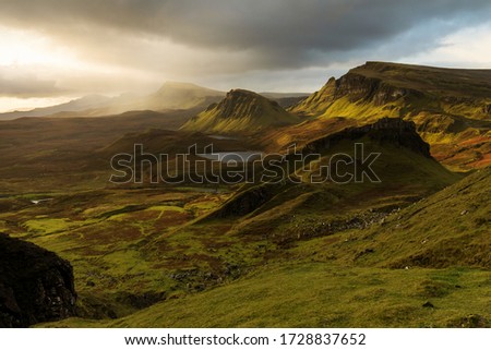 Scenic view of Quiraing mountains in Isle of Skye, Scottish highlands, United Kingdom. Sunrise time with colourful an rayini clouds in background
