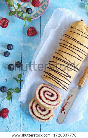 Vanilla Sponge Cake Roll with Berry Jam. Flat layot. Blue background