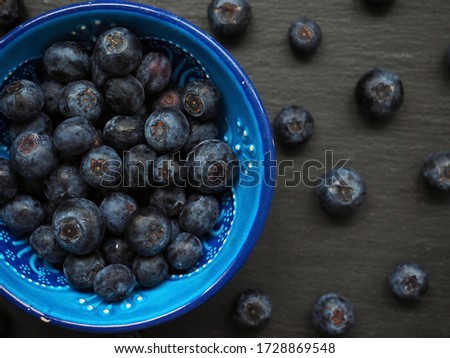 Fresh blueberries in blue bowl on black background