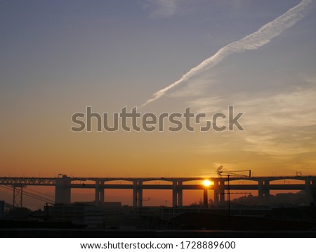 This is a picture taken from a park in Lisbon, looking a the Bridge of the 25th of April with the sunset shining through