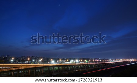 The beautiful city night view with the highway lights and moon and stars in the night sky