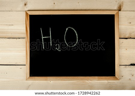 school blackboard on wooden table with "H2O" written on it