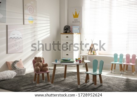 Small table and chairs with bunny ears in children's room interior