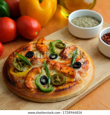 Small Pizza served on a wooden platter with vegetables and spices