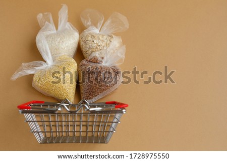 various groats in packages in a grocery basket on a brown background. Rice and oatmeal, buckwheat and millet