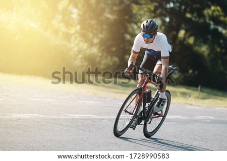 Cyclist pedaling on a racing bike outdoors in sun set .The image of cyclist in motion on the background in the evening. Royalty-Free Stock Photo #1728990583