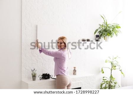 Happy european girl holding a blank canvas in her hands. Empty frame for text or photo. Young woman with mockup poster