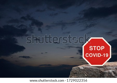 Stop COVID-19 outbreak icon plate on rock mountain over sunset sky, Global epidemic alert, Concept of novel coronavirus outbreak