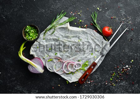 Black cooking background. Rosemary and spices on a black stone table. Top view. Free space for your text.