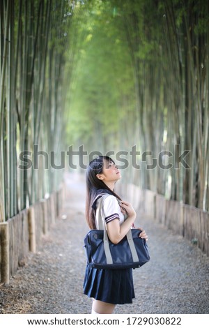 Portrait of beautiful Asian japanese high school girl uniform looking with bamboo forest background