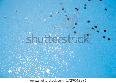 Holiday background with little silver stars on classic blue glittering background. Copyspace top horizontal view