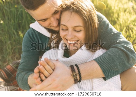 

A guy and a girl love each other, smile, hug, kiss, laugh, enjoy life in the forest on the beach. A girl takes a picture of a guy's camera on a cliff, sunset on the background.