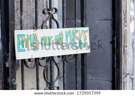hand painted signboard saying in german language: entrance only with mask