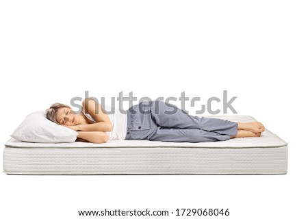 Young woman in pajamas sleeping on a comfortable mattress isolated on white background Royalty-Free Stock Photo #1729068046