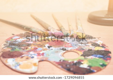 Art artist background, palette with paints and brushes on the table, hobby