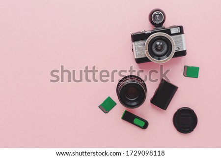 camera, memory cards, battery, lens on a pink background, the concept of studying photography