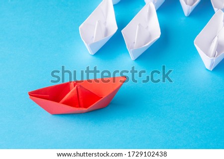 A red ship as a leader. White following it. Blue background. Place for text