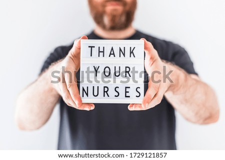 Nurse day concept. Man hands holding lightbox with text Thank your nurses thanking doctors, nurses and medical staff working in hospitals during coronavirus COVID-19 pandemics