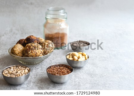 Vegetarian food-energy balls, on a gray background in a Cup, next to Chia seeds, flax, sunflower, peanuts. Nutritious snack. Close-up, selective focus,