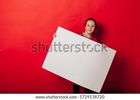 Schoolgirl's girl holds sign for inscriptions on red background