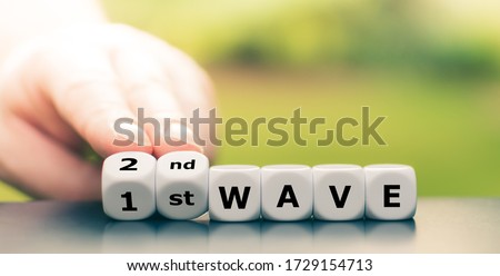 Symbol for a second wave of the corona virus. Hand turns dice and changes the expression "1st wave" to "2nd wave" Royalty-Free Stock Photo #1729154713