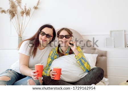 Cute children in 3d glasses watching movie on the bed at home.Eat popcorn. Family concept, no gadgets. happy mom and kids. Mothers Day.