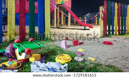 Scattered plastic toys near a playground closed with prohibition tape