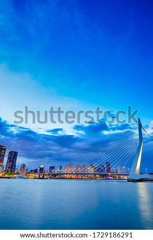 Dutch Travel Destination. View of Renowned Erasmusbrug (Swan Bridge) in  Rotterdam in front of Port and Harbour. Picture Made At Dusk. Vertical image