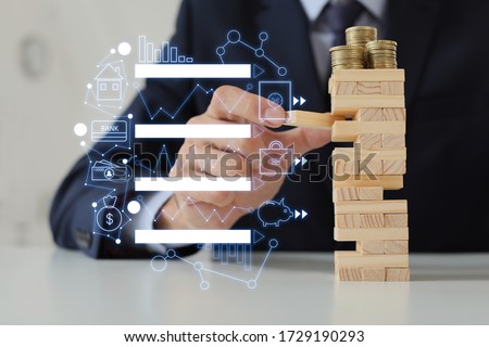 Male bank manager with tower made of blocks and coins at table in office. Concept of planning, risk and strategy in business Royalty-Free Stock Photo #1729190293