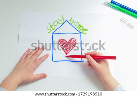 Top view of hands of little girl painting heart in house on sheet of paper during coronavirus at home. Children's creativity. Stay Home concept.